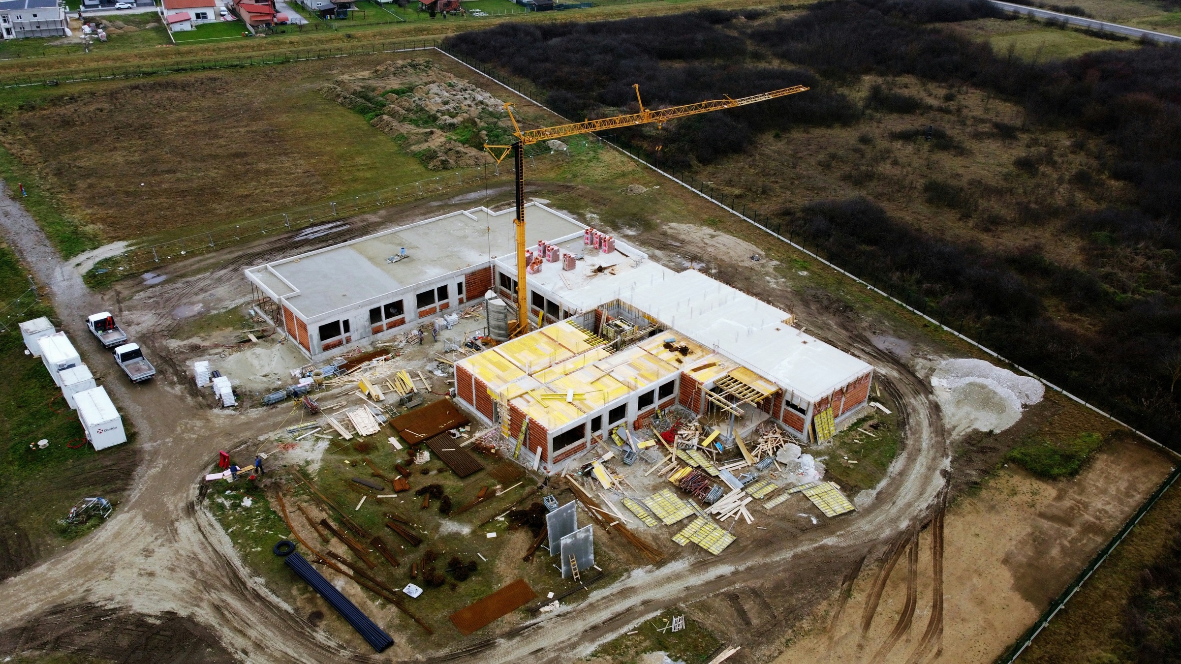 Aerial view of a commercial construction site mid-build with a yellow tower crane